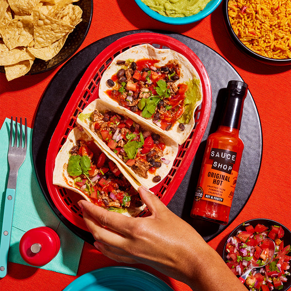 Sauce Shop Original Hot Sauce Pulled Chicken Tacos with Kidney Beans and Red Pepper Served with Sides of Tortilla Chips, Guacamole and Rise